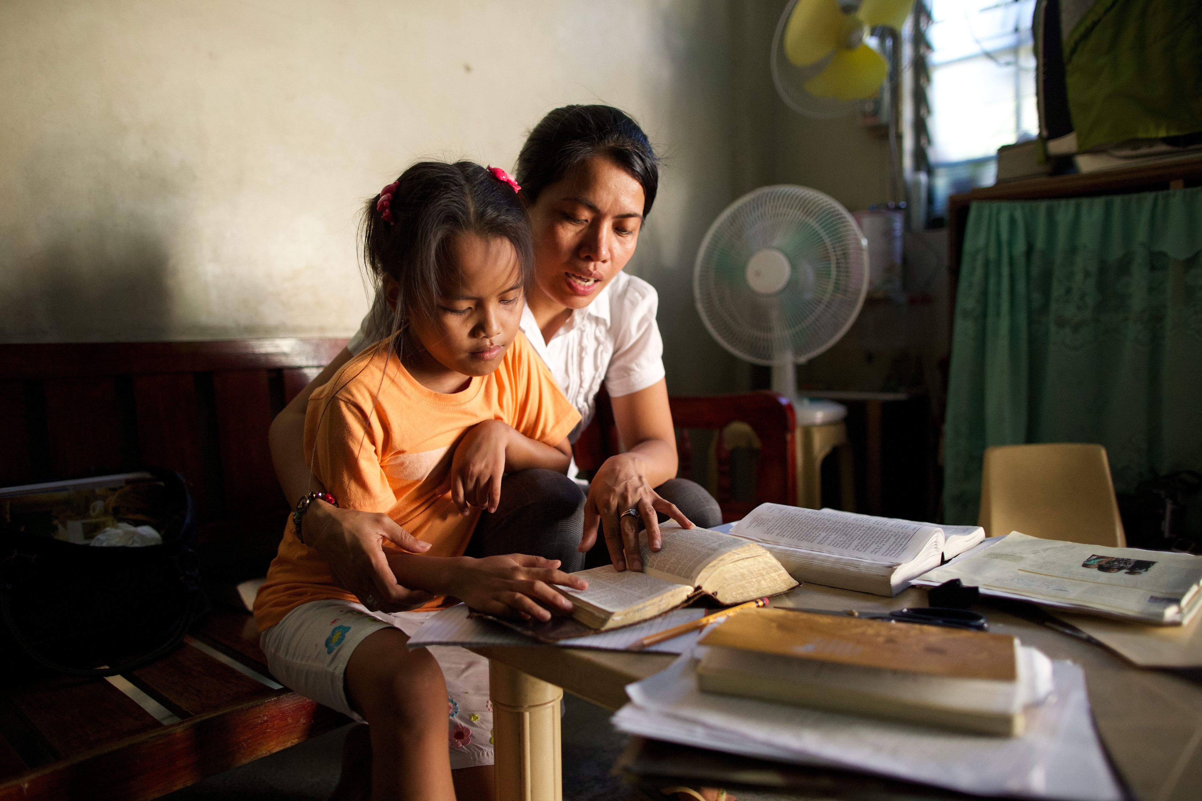 A woman reads the scriptures with her young daughter.