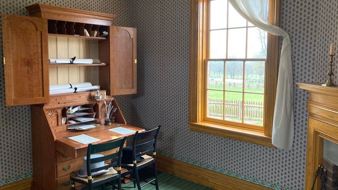 Home office setting with two chairs in front of a secretary desk.