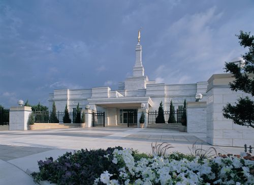 The Oklahoma City Oklahoma Temple during the day, with spring flowers in a flower bed in front of the temple.