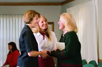 Two women welcoming another woman to Relief Society.