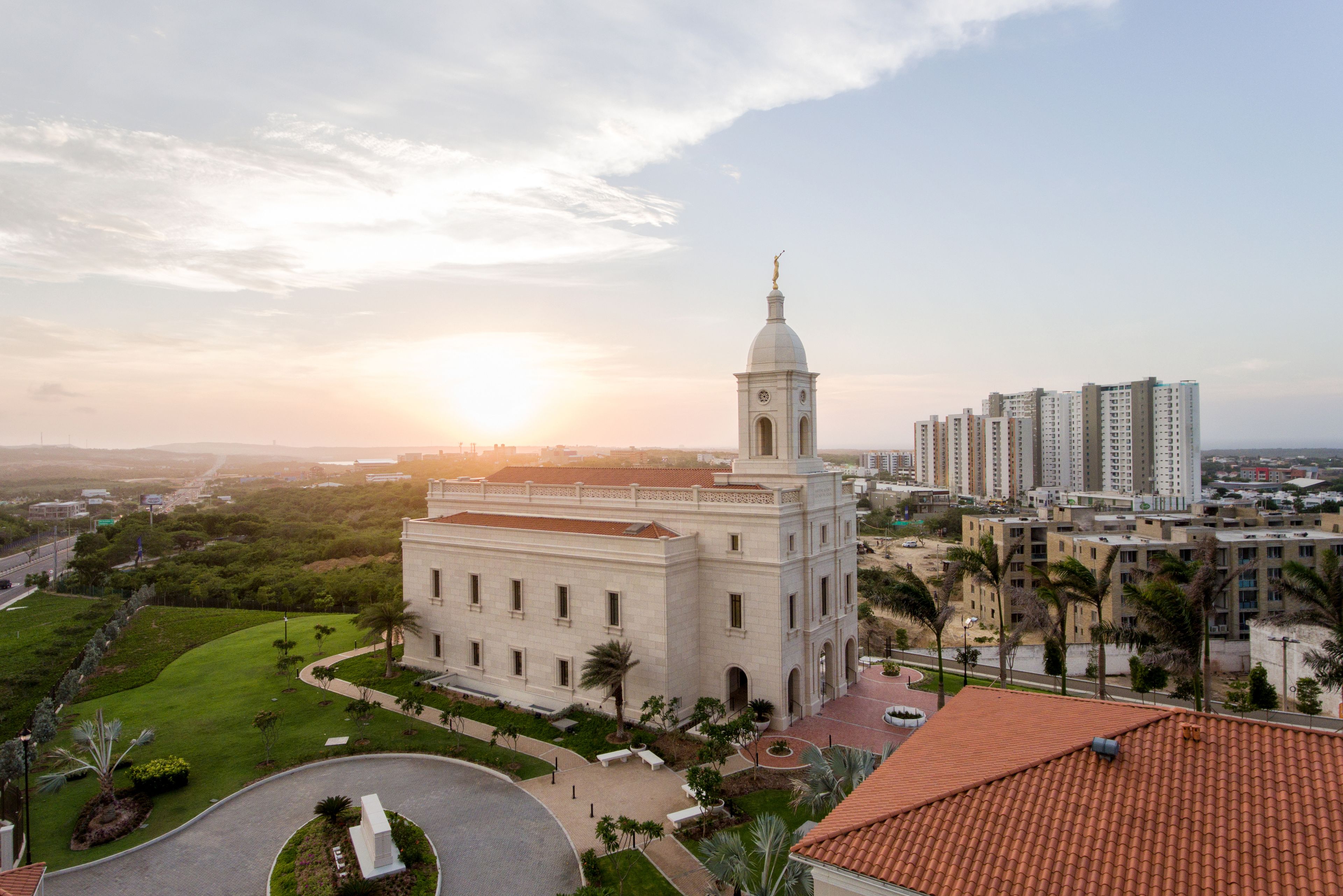 A side view of the entire Barranquilla Colombia Temple, surrounded by landscaping and city buildings.