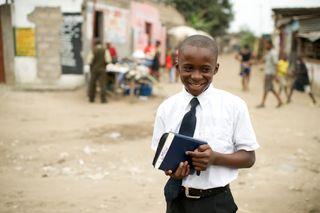 young boy holding scriptures and smiling