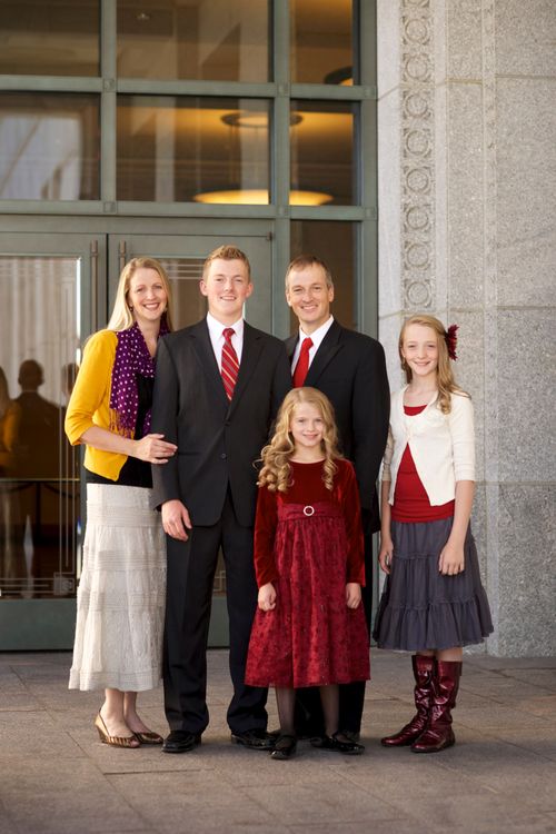 A father and mother standing and smiling with their tall son and two young daughters outside the Conference Center doors.