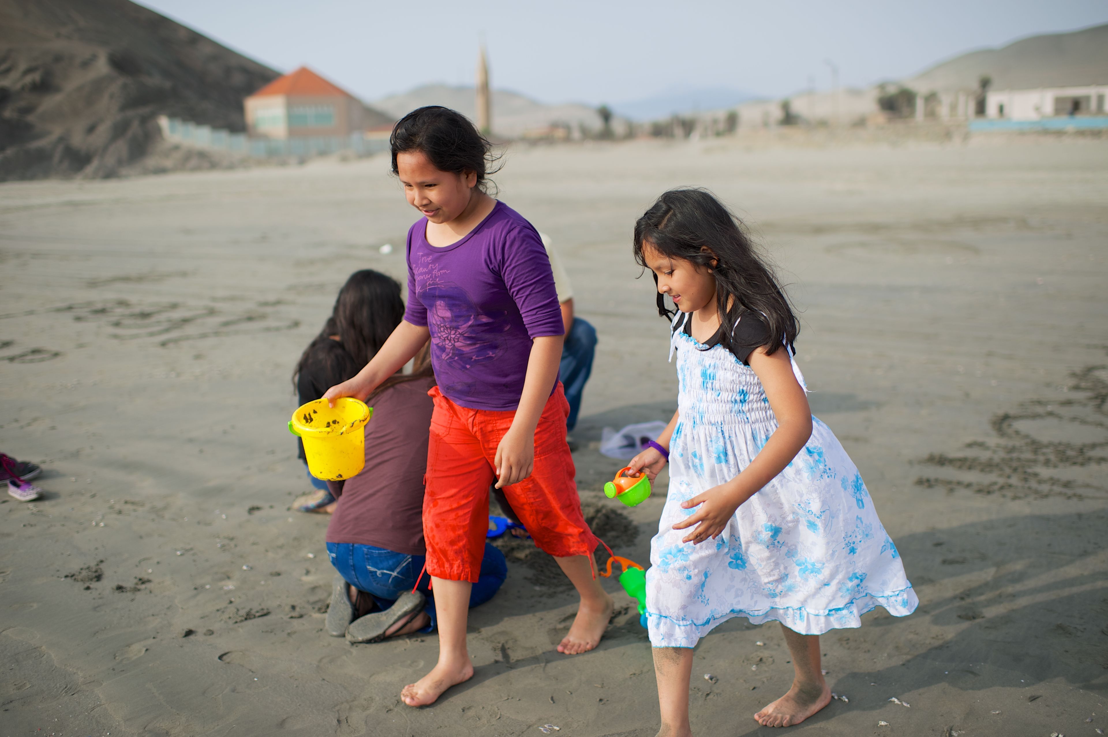 A Peruvian family plays outside in the sand.  