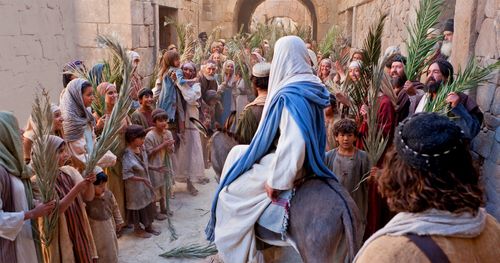 Jesus is riding a colt into Jerusalem through a great multitude of people holding tree branches. Outtakes include Jesus barely seen in a throng of people, images of the crowd, some small children, and Jesus walking through the crowd.