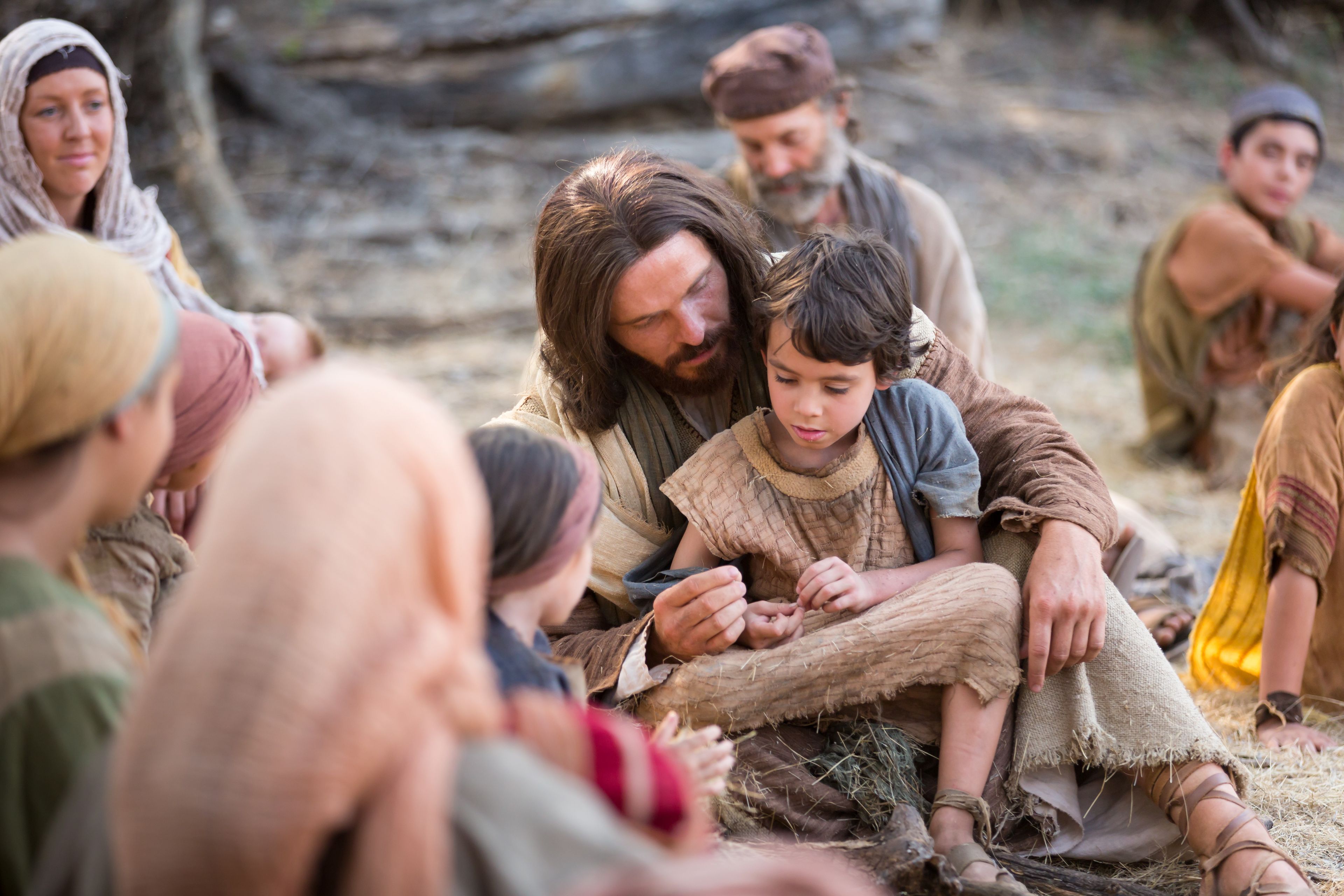 Jesús se sienta con un niño después de decir a Sus apóstoles: “Dejad a los niños venir a mí”.