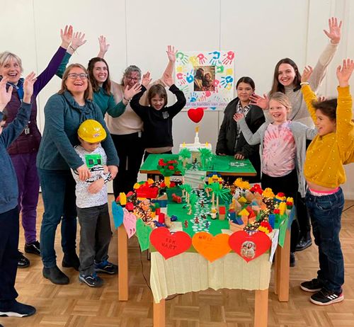 A group of primary children with their leaders celebrate creating a large Lego style town with a Temple.