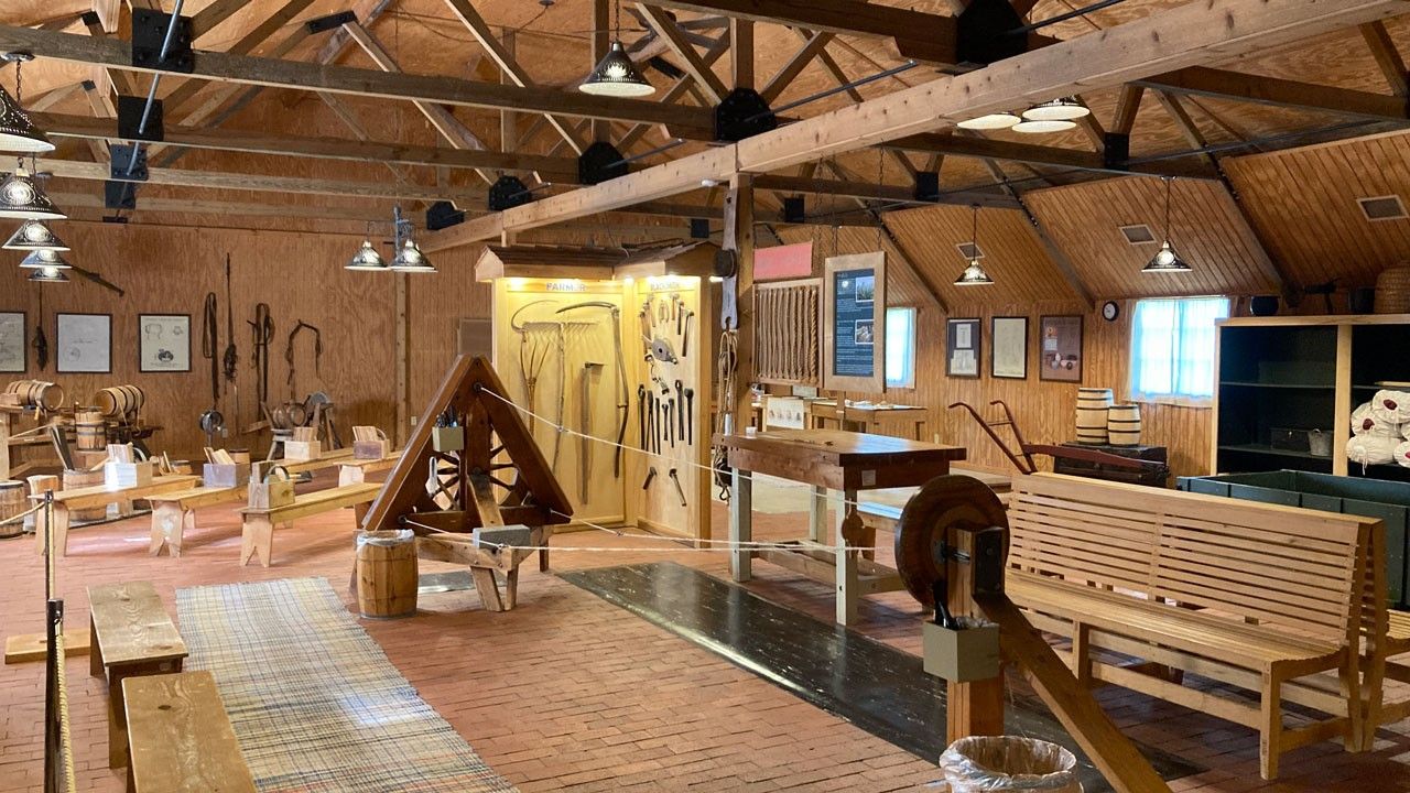 Interior of Family Living Center. A rope making machine is in the foreground and a barrel making station is in the background.