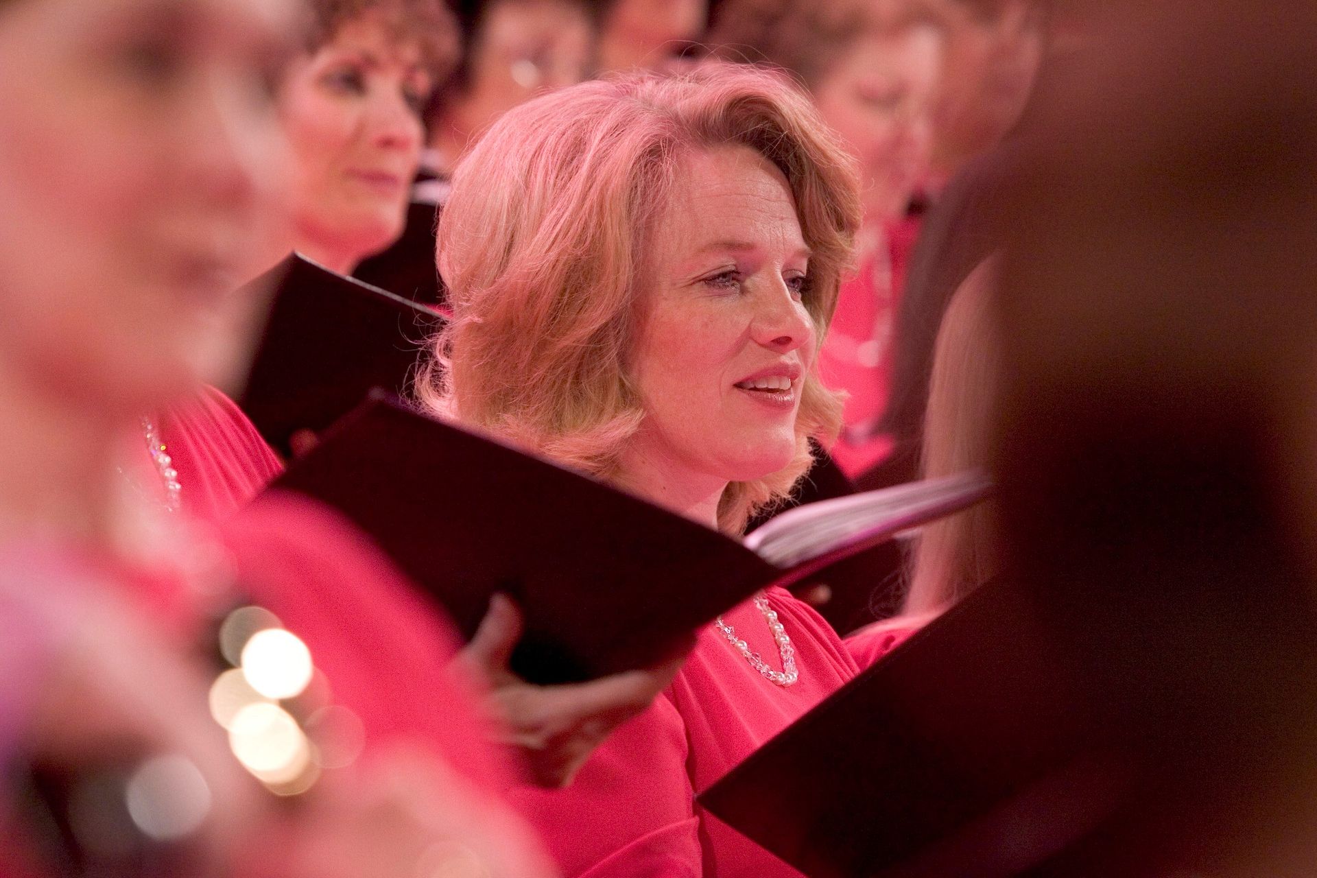 A woman in the Mormon Tabernacle Choir sings while holding her music.