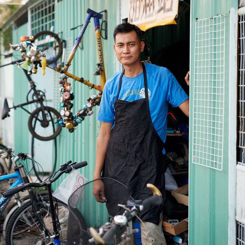 man standing in front of his bicycle shop