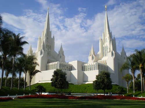The entire San Diego California Temple, with a view of the grounds, lined with trees, flowers, and bushes.