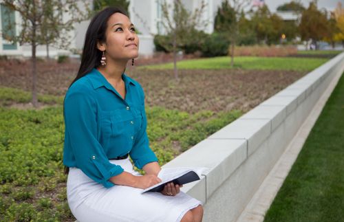 a woman sitting in front of the temple and looking at the sky