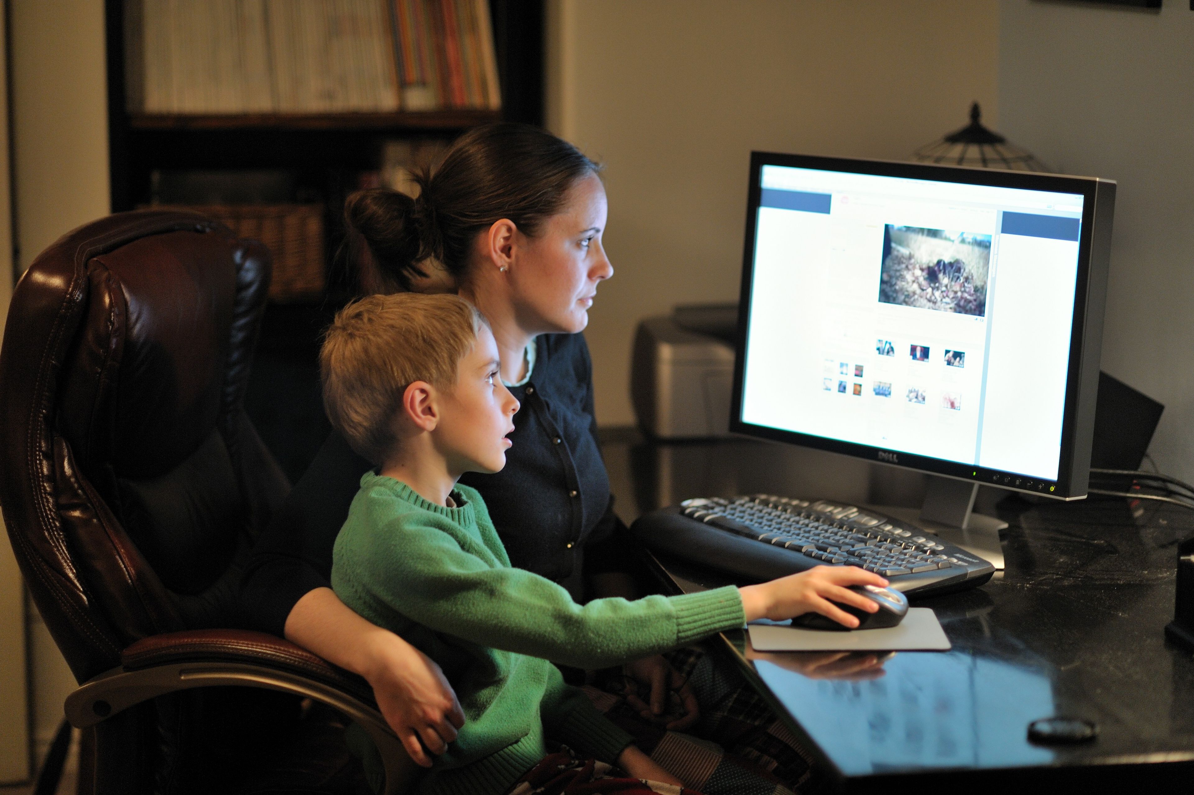 A mother sits at her computer with her son and looks at LDS.org.  