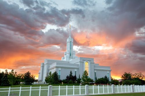 A front side view of the Mount Timpanogos Utah Temple during sunset, with pink and orange clouds over the temple’s spire.