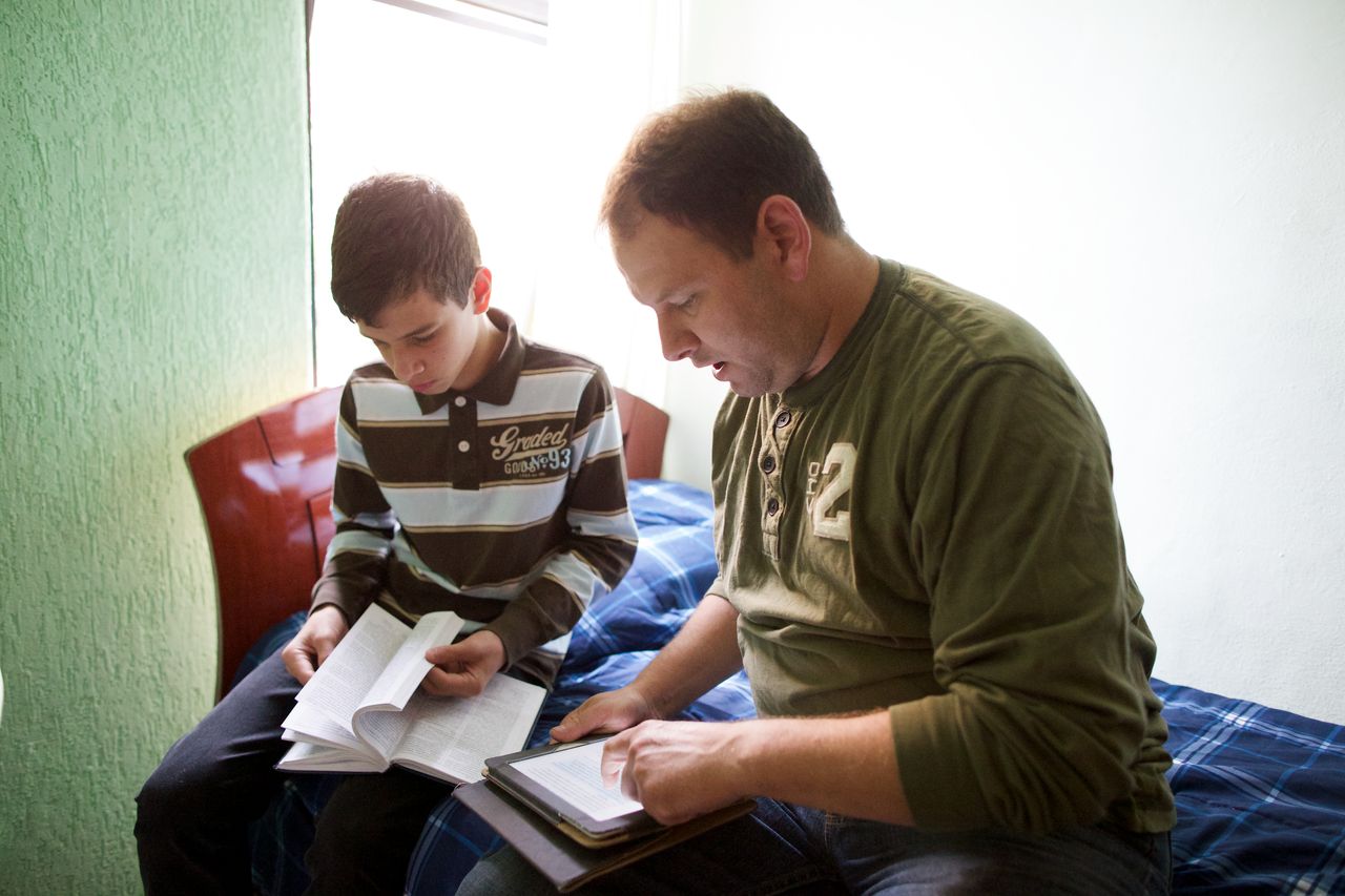 Um homem estuda as escrituras com seu filho