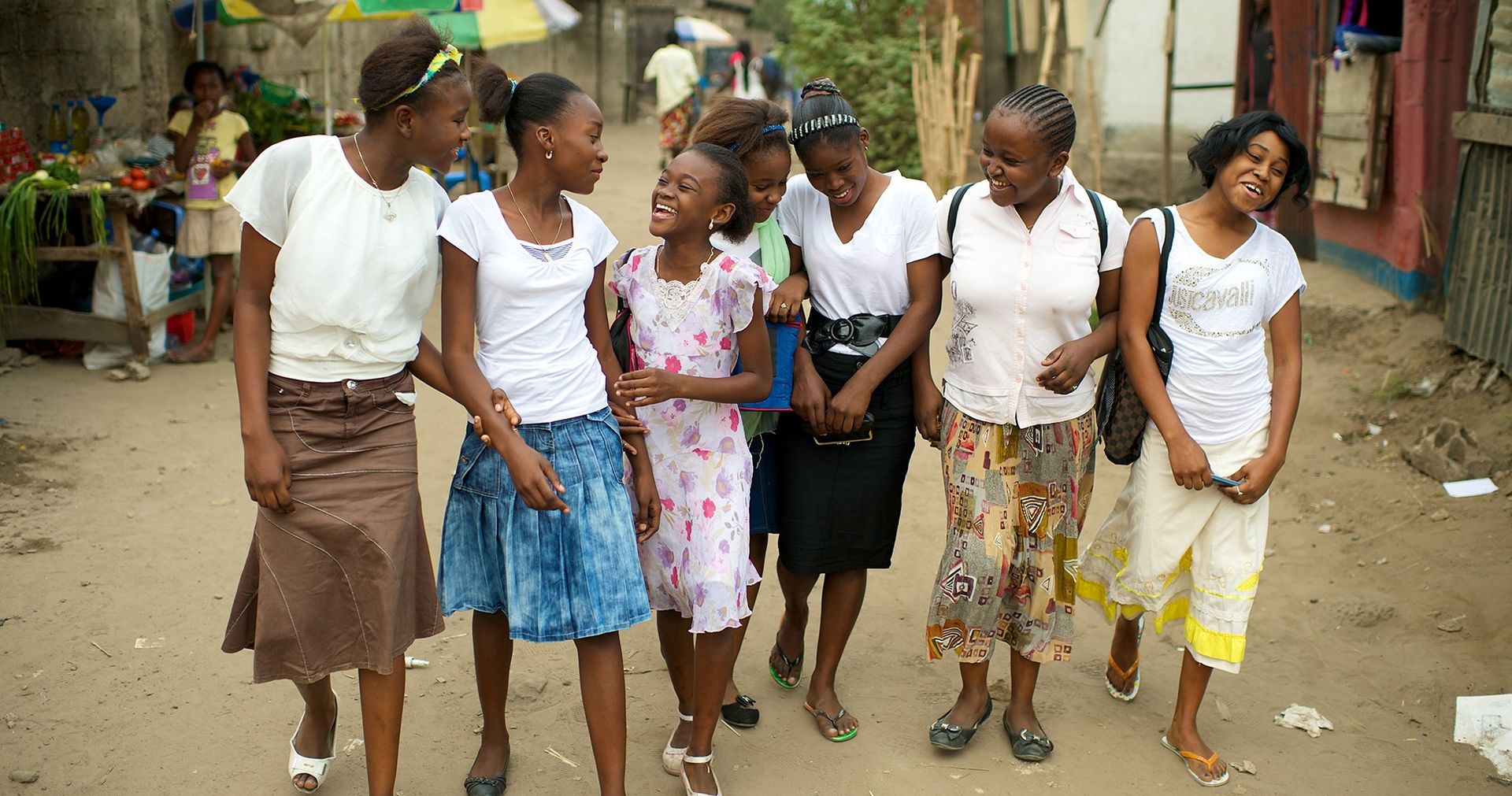 A group of women and young women from the Democratic Republic of the Congo (DRC) in Africa walking together enjoying each others company.  There is a street in the background.