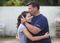 A teenage girl is outside with her father in the garden of their home in Puerto Rico. She is giving her father a hug.