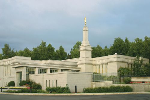 A view of the entire Anchorage Alaska Temple on a sunny sumner day, with green lawns and plants on the grounds.