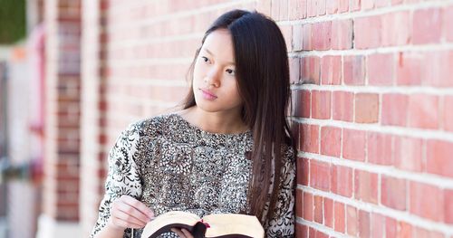 Young single adult reading her scriptures deep in thought