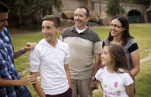 A smiling family standing on a lawn.  Shot in Australia.