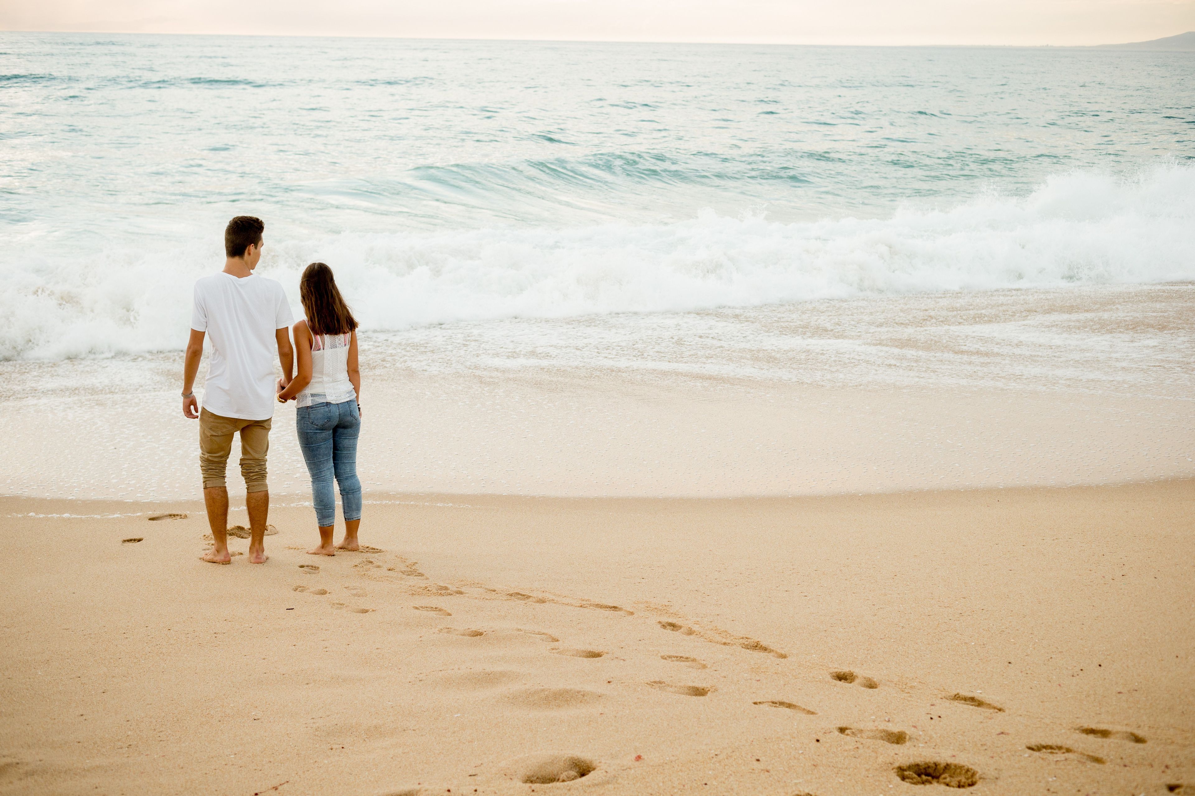 A young couple from Portugal standing on the beach and looking over the ocean.