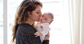 a mother kisses her baby