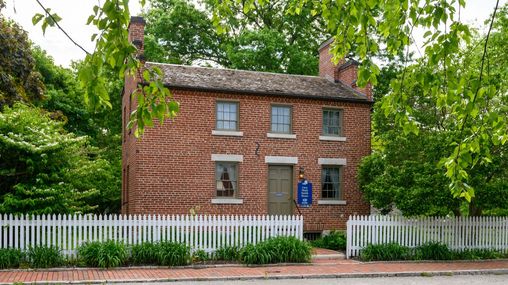 Two-and-a-half-story brick home with a white picket fence.