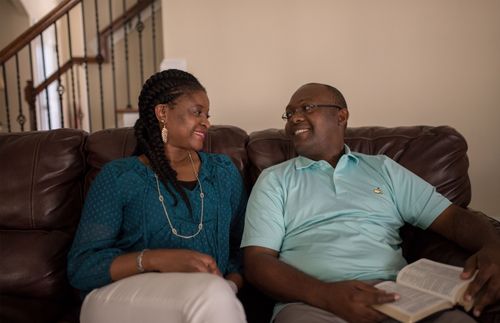 a couple sitting on a couch and smiling at each other