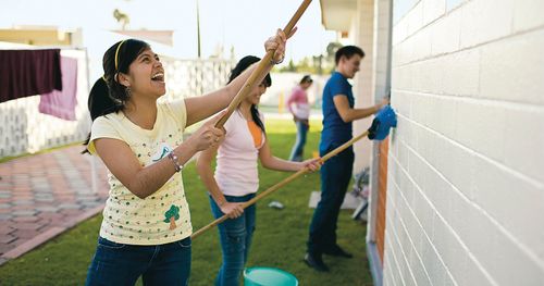 Youth in Mexico washing down the outside of a house during a service project.