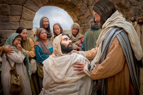 A man looking up to Christ, who has healed him, while others watch in the background.