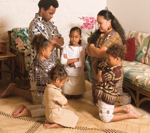 A Polynesian family kneeling in family prayer.