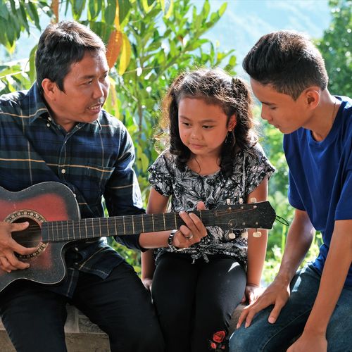 father playing guitar to daughter and son