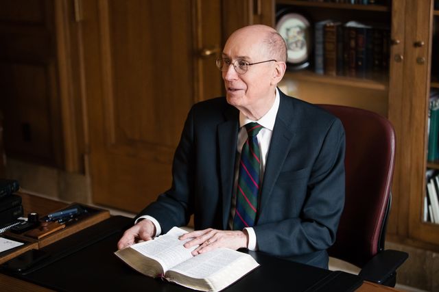 President Henry B. Eyring sits in his office. He is holding a set of scriptures and reading.