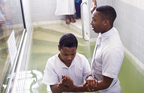 young man being baptized in a baptismal font