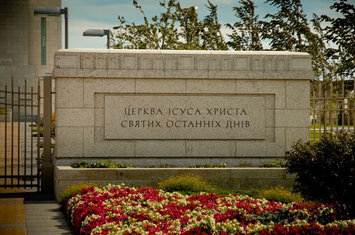 The granite sign outside of the gate to the Kyiv Ukraine Temple, with colorful flowers in front of it.