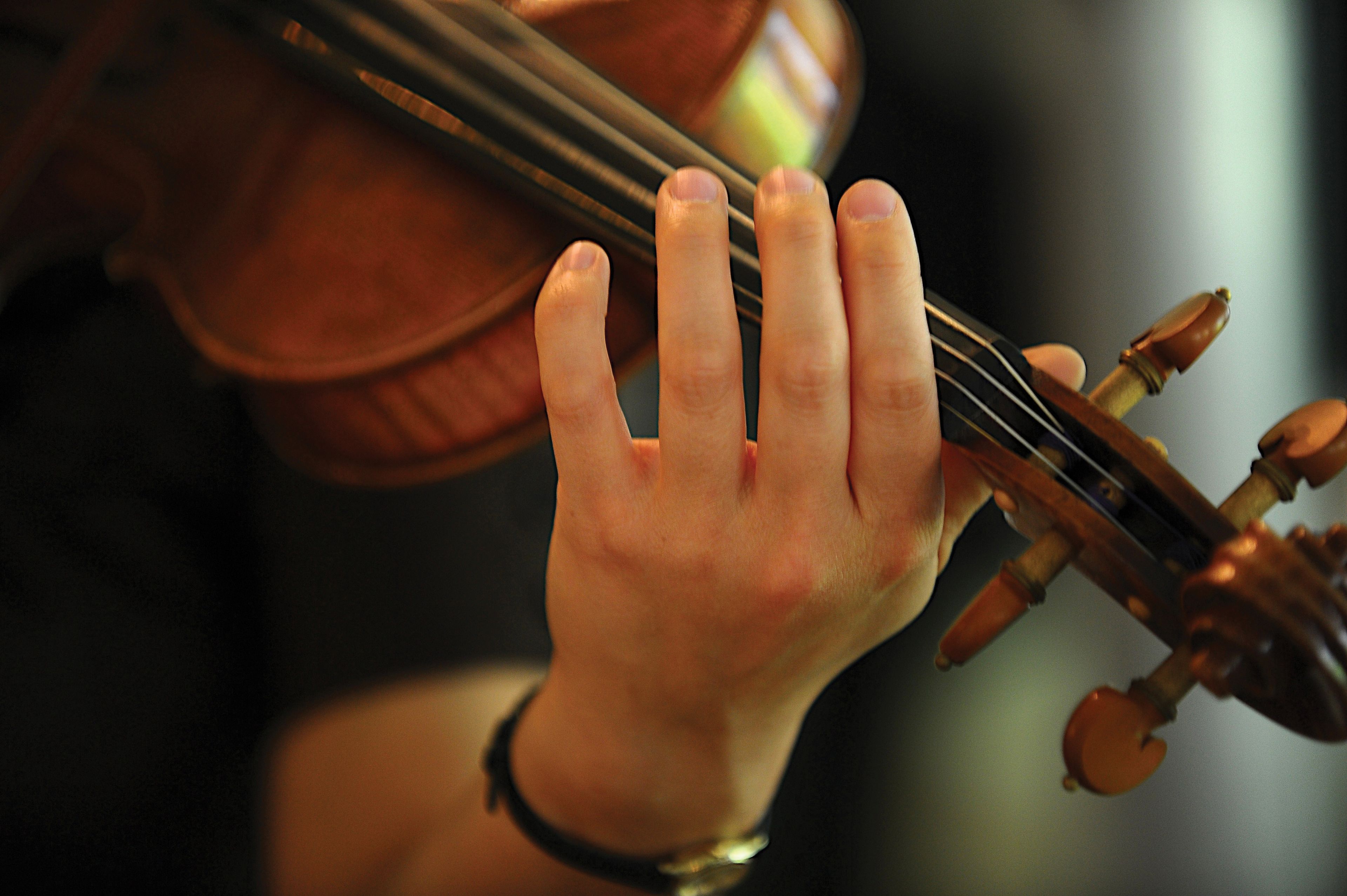 A close-up image of a hand playing on a violin.