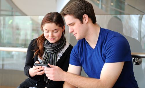 young woman and young man looking at smartphone
