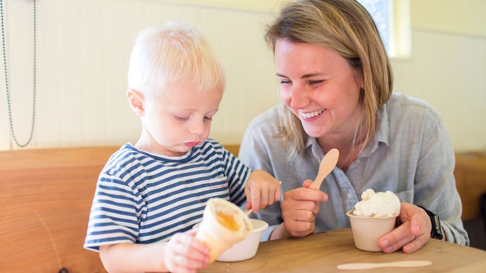 A woman and small child enjoying ice cream in a restaurant.