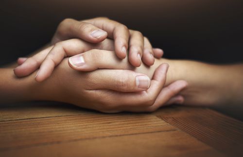 close-up of one person’s hand being held by another person’s hands