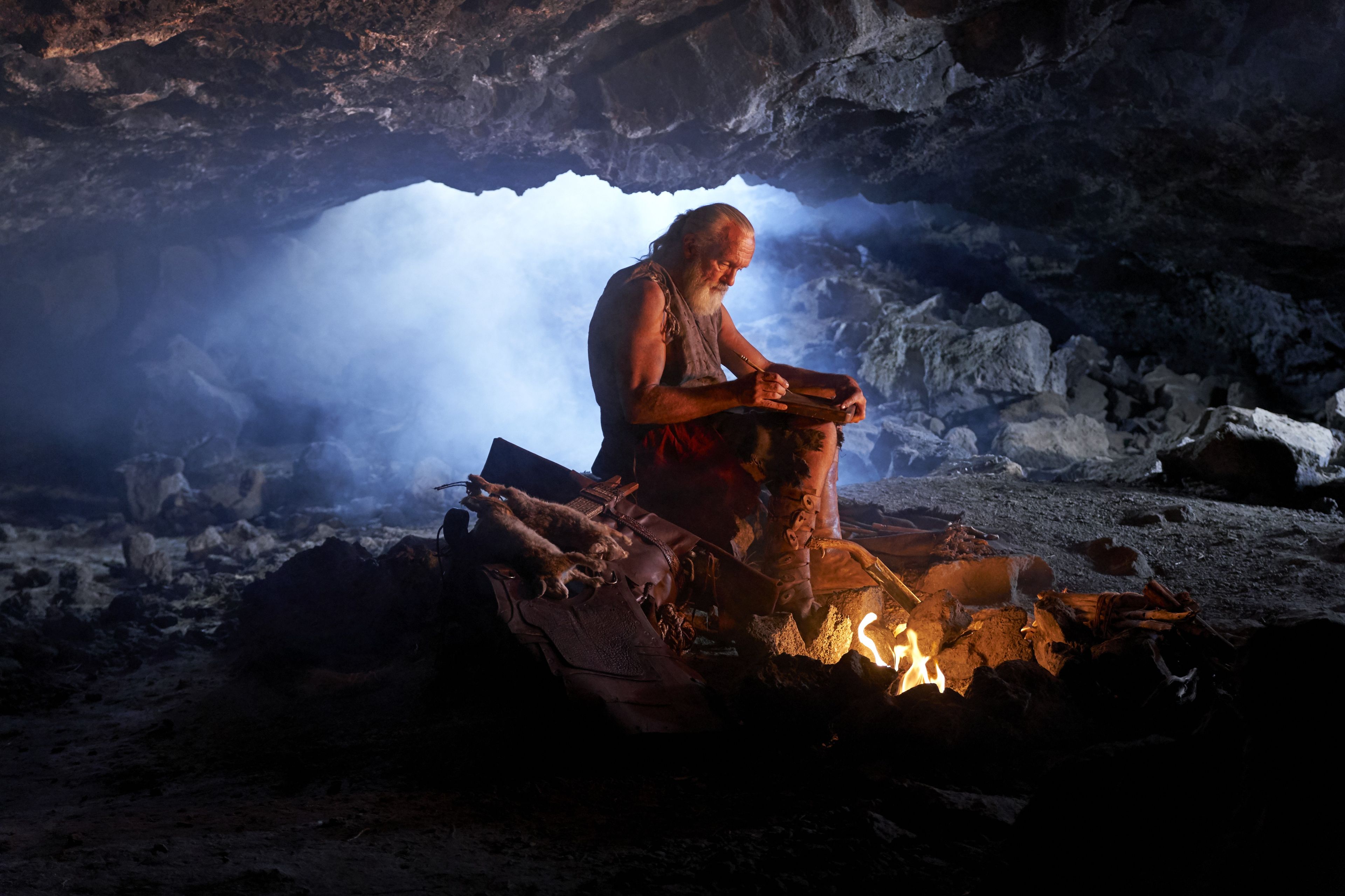 Moroni, son of Mormon, writes by a fire as he dwells in the cavity of a rock.