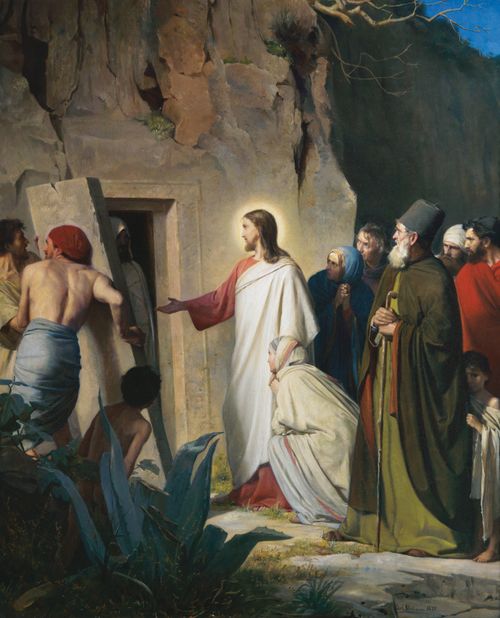 A painting by Carl Bloch of Christ in a white and red robe standing in front of Lazarus’s tomb while Lazarus walks out of the door.