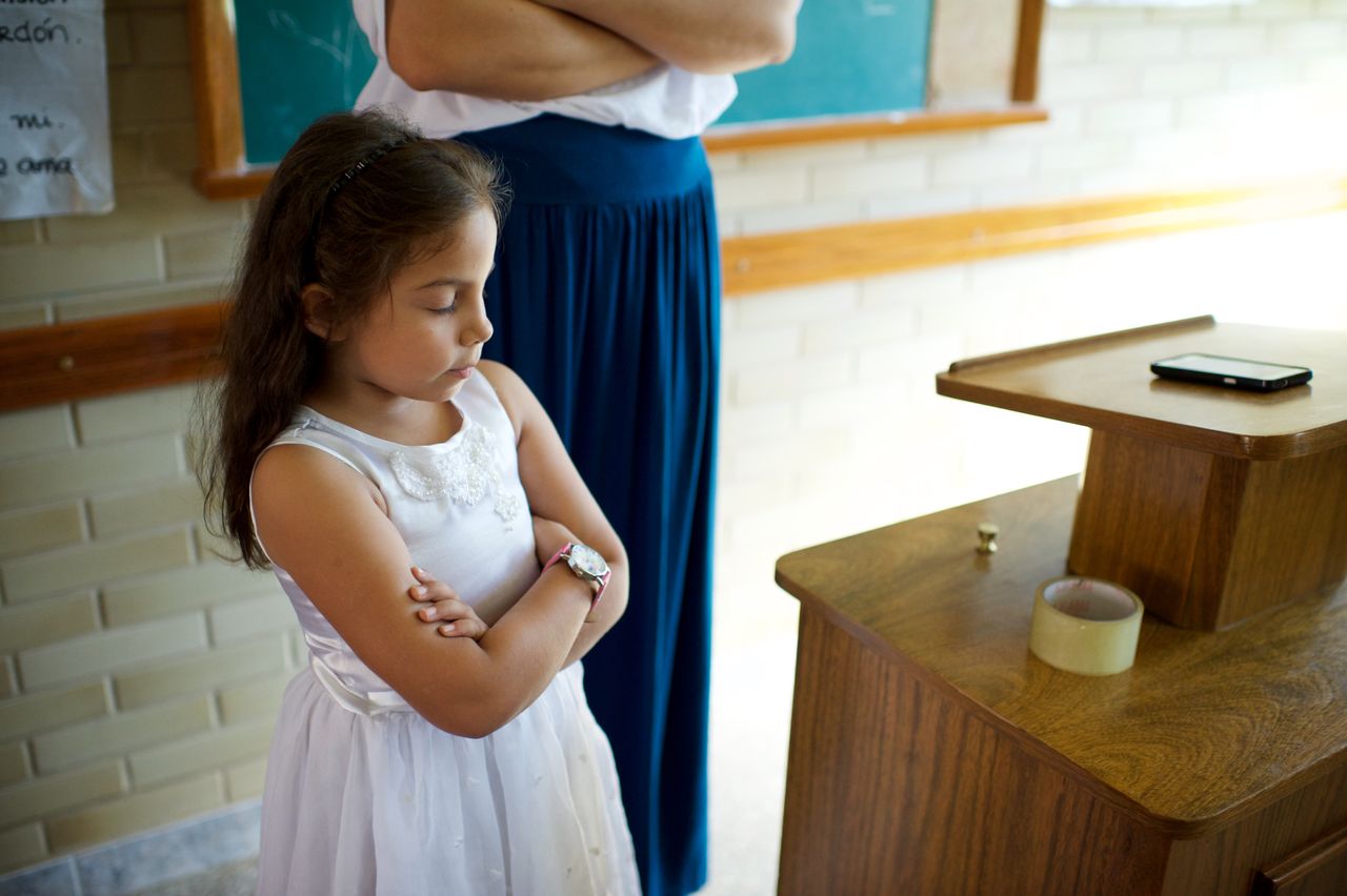 Uma menina cruza os braços em oração em uma reunião da Primária