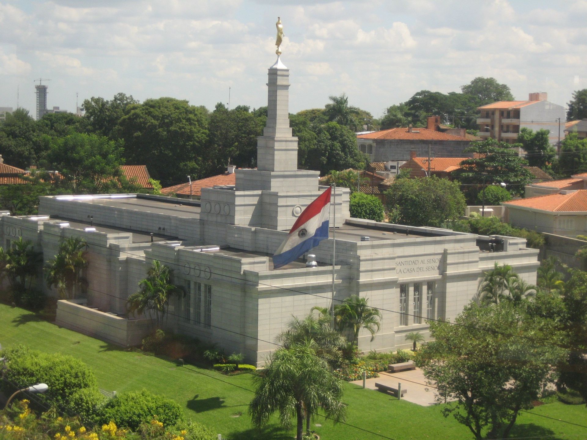 The Asunción Paraguay Temple situated in the local community, with the Paraguayan flag on display.