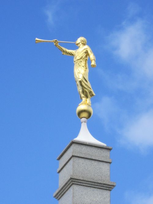 The angel Moroni statue on top of the Melbourne Australia Temple, with a blue sky behind.