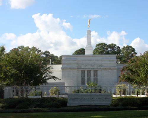 The stone name sign in front of the Columbia South Carolina Temple, surrounded by a green lawn and trees.