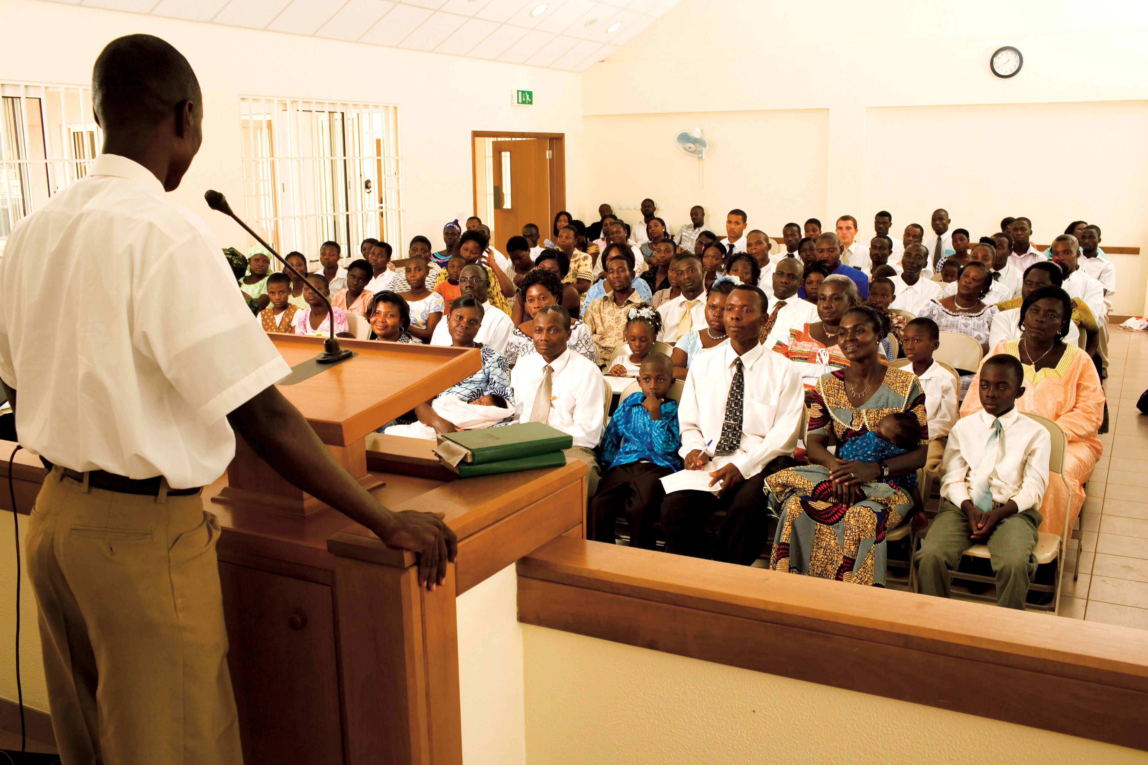 A speaker standing in front of a congregation, giving a talk.
