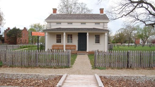 A one-and-a-half-story white clapboard home with a large front porch.