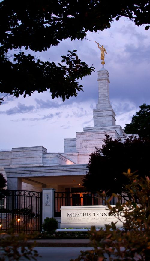 A portrait view of the Memphis Tennessee Temple in the evening, with the temple name sign lit up in front.