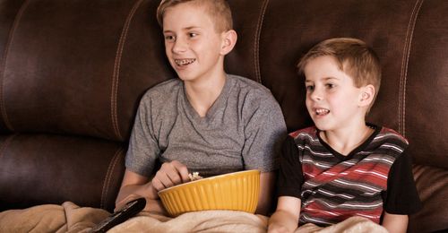 young men watching TV with popcorn