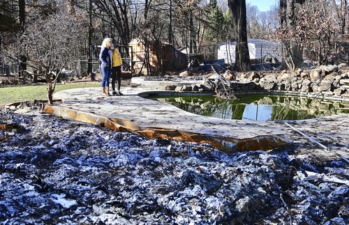 mother and daughter walking through ruins of home